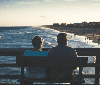 a couple sitting on a bench near the ocean
