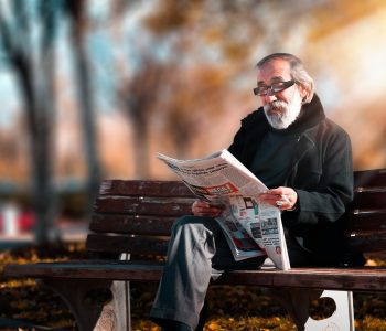 man on bench reading a newspaper